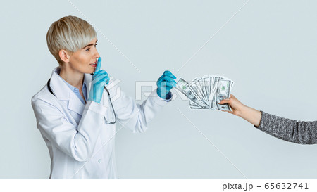 Woman doctor in medical gloves takes money from patient hands and makes sign of silence Woman doctor in medical gloves takes money from patient hands and makes sign of silence 65632741