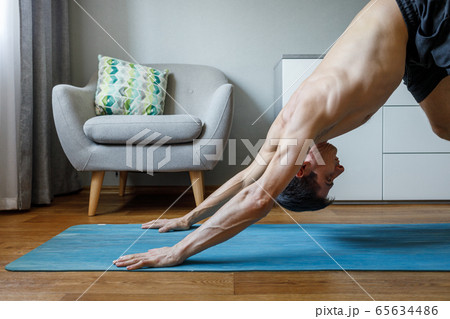 Man in upward dog pose doing vinyasa flow at home. 65634486
