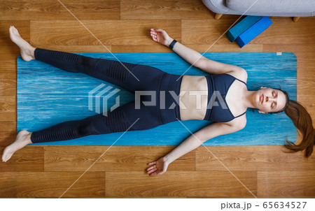 Young yogi woman relaxing in shavasana pose home 65634527