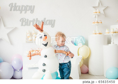 Cute little boy with blond hair on his birthday at a children's party with balloons and cakes. Children's party. Balloons 65635450