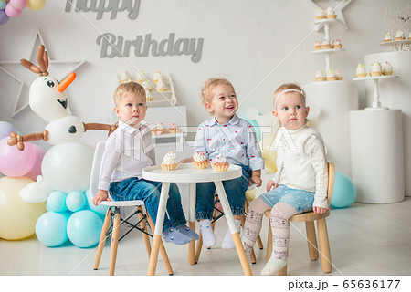 Cute little boys and girl at a table with birthday cakes at a children's party with balloons. Children's party. Balloons 65636177
