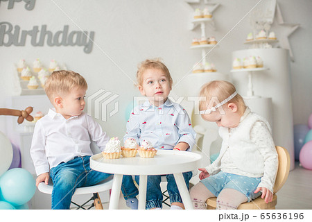 Cute little boys and girl at a table with birthday cakes at a children's party with balloons. Children's party. Balloons 65636196