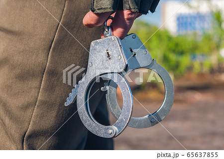 Handcuffs in the hands of a policeman close-up. Police equipment part 65637855