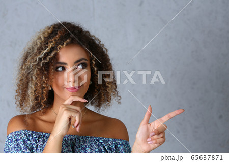 A black woman on a gray background points a finger at the air to an inscription that you can write to enter 65637871