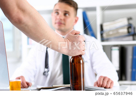 Alcoholic hold in hand empty bottle at doctor reception Alcoholic hold in hand empty bottle at doctor reception 65637946