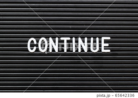Black felt board with white alphabet in word continue background 65642336