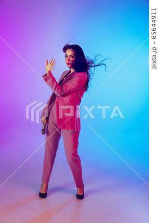 Caucasian female singer portrait isolated on gradient studio background in neon light 65644911