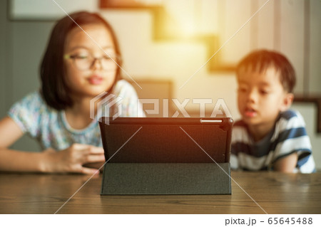 Selective focus on the tablet on the table with blurred students learning at home Selective focus on the tablet on the table with blurred students learning at home 65645488