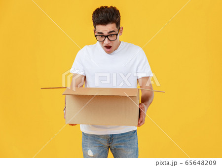 Astonished man looking inside carton box 65648209