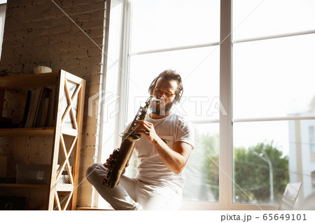Caucasian musician playing saxophone during online concert at home isolated and quarantined, impressive improvising 65649101