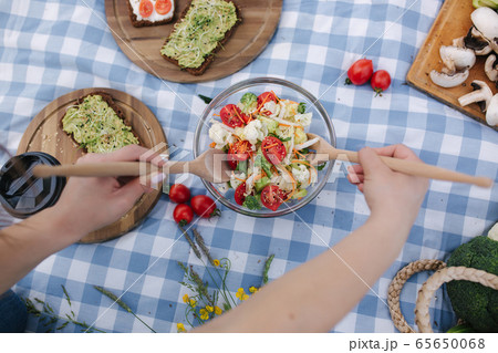 First person view of Woman mix vegan salad on picnic outside. Vegan food concept 65650068