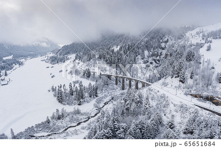 Aerial View of the Landwasser Viaduct with Railway without famous train at winter, landmark of Switzerland, snowing, river and mountains 65651684