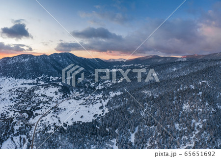 The Aerial view of a sunset over mountain in Arahova, Greece, a view of the valley below with trees covered by snow, colors of sunset 65651692