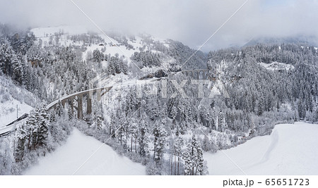 Aerial View of the Landwasser Viaduct with Railway without famous train at winter, landmark of Switzerland, snowing, river and mountains 65651723