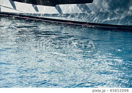 Board of the big boat of grey color, reflections of the sun on water at sunset, interesting texture, smooth lines of water 65652098