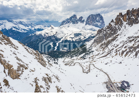 Aerial view of twisting road in the mountains of Italy, is serpentine among the snow-covered hills, is famous place among skiers and fans to understand a known by sports cars, mountains peak 65652473