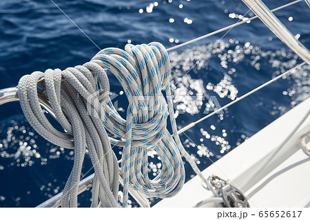 Close-up view of sailboat ropes at sunny weather, pulleys and ropes on the mast, Yachting sport, ship equipment, sea is on background Close-up view of sailboat ropes at sunny weather, pulleys and ropes on the mast, Yachting sport, ship equipment, sea is on background 65652617
