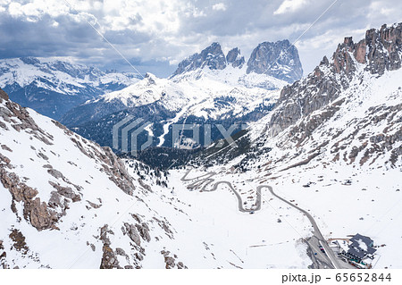 Aerial view of twisting road in mountains of Italy, Dolomites, is serpentine among the snow-covered hills, is famous place among skiers and fans to understand a known by sports cars, mountains peak 65652844