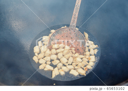 Roasting of mutton fat to a condition of crackers, some stage of preparation of a national Uzbek dish pilaf, shovel for food, cauldron, fire, firewood, outdoor 65653102