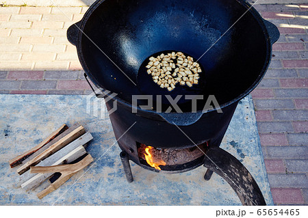 Roasting of mutton fat to a condition of crackers, some stage of preparation of a national Uzbek dish pilaf, shovel for food, cauldron, fire, firewood, outdoor Roasting of mutton fat to a condition of crackers, some stage of preparation of a national Uzbek dish pilaf, shovel for food, cauldron, fire, firewood, outdoor 65654465