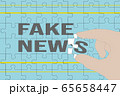 Hand holding a puzzle piece completing fake news words 65658447