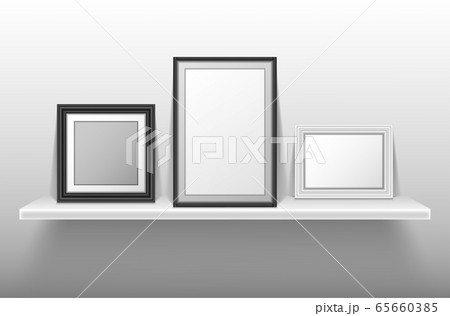 Empty photo frames standing on white shelf Empty photo frames standing on white shelf 65660385