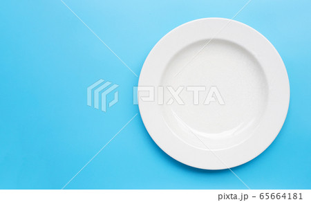 Empty white ceramic plate on blue background. Empty white ceramic plate on blue background. 65664181