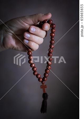 womans hand with wooden rosary or prayer beads womans hand with wooden rosary or prayer beads 65665655