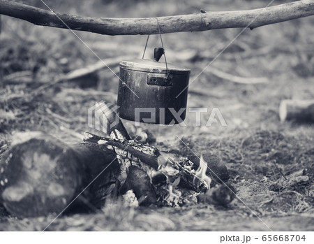 Outdoor cooking in old sooty cauldron on campfire 65668704