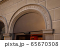 Building with a showcase. Empty plate in the form of an arch on an old house. Empty space for a number, text or store name on glass. Side view from below. Black metal minimal design for advertising. 65670308