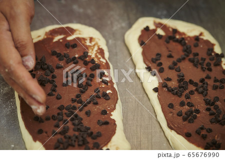 パン生地にチョコチップを乗せるパン職人 ベーカリーイメージ パン生地にチョコチップを乗せるパン職人 ベーカリーイメージ 65676990
