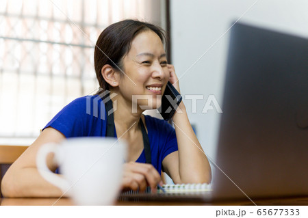 Happy woman talking on cell phone with open laptop on table work at home concept. Happy woman talking on cell phone with open laptop on table work at home concept. 65677333