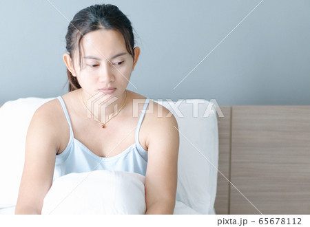 Closeup woman sitting on bed in the bedroom Closeup woman sitting on bed in the bedroom 65678112