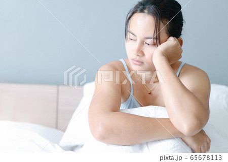 Closeup woman sitting on bed in the bedroom Closeup woman sitting on bed in the bedroom 65678113