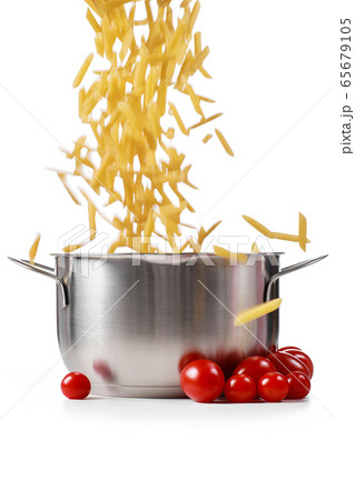 Raw pasta poured into a saucepan on a white background. Raw pasta poured into a saucepan on a white background. 65679105