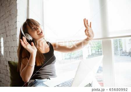 Caucasian female singer during online concert at home insulated and quarantined, cheerful and happy, singing live, performing 65680992