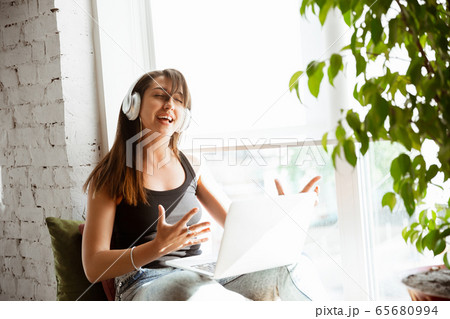 Caucasian female singer during online concert at home insulated and quarantined, cheerful and happy, singing live, performing 65680994
