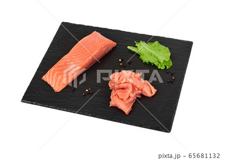 Sliced salmon fillet on the black shale board, with lemon and salad. On white background 65681132