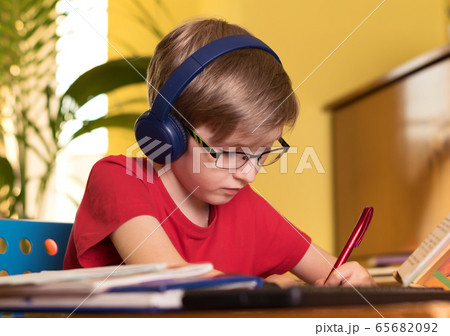 blond boy does homework at the table in headphones blond boy does homework at the table in headphones 65682092