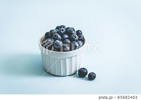 Fresh raw organic blueberry in mug on a blue 65682403