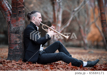 young man plays golden trumpet in gloomy autumn young man plays golden trumpet in gloomy autumn 65684171