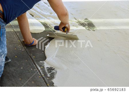 A construction worker troweling mortar onto 65692183
