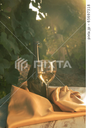 glass with white wine in vineyard on old table glass with white wine in vineyard on old table 65697318
