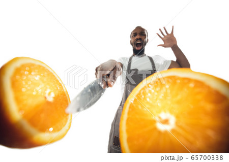 Amazing african-american man preparing unbelievable food with close up action, details and bright emotions, professional cook. Cutting orange on the fly 65700338