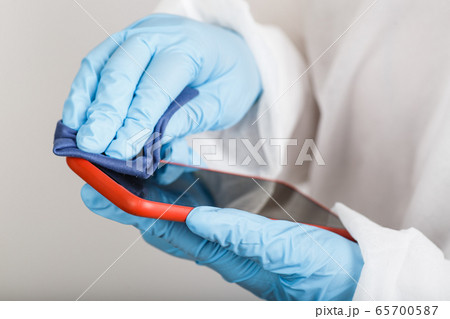 Hands in protective gloves cleaning phone from viruses Hands in protective gloves cleaning phone from viruses 65700587