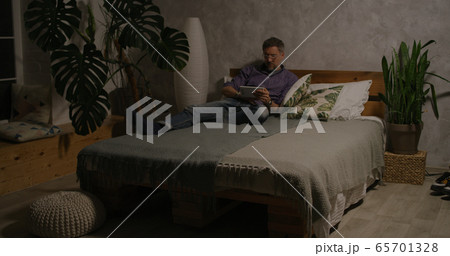 Man switching lighting on and off with home hub 65701328