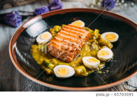 grilled salmon sauce end eggs on a black plate 65703095
