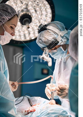 Team of women surgeons in the operating room. A modern team of doctors during an ancological operation. Fight against cancer. Reconstructive plastic surgery after cancer 65703649