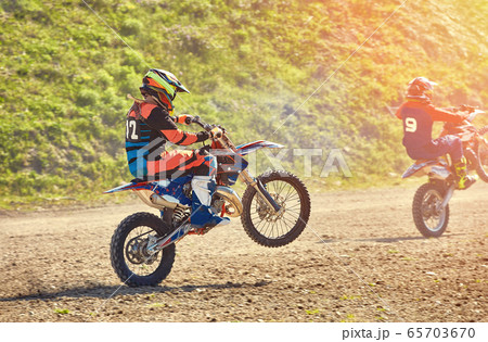 A team of mountain bike athletes starts, smoke and dust fly out from under the wheels off-road. Motocross outdoor activity concept. A team of mountain bike athletes starts, smoke and dust fly out from under the wheels off-road. Motocross outdoor activity concept. 65703670