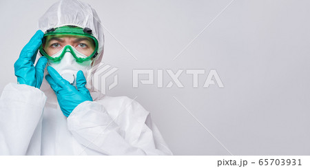 Doctor is wearing PPE - costume, gloves and surgical face mask. 65703931